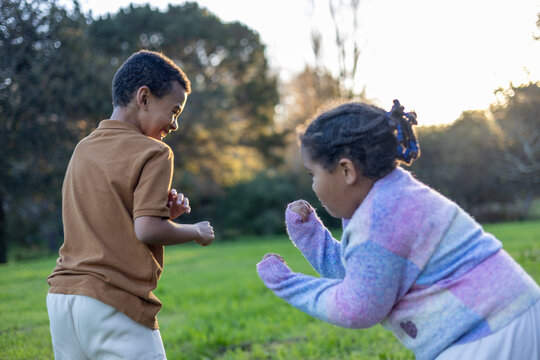 Children play fighting outdoors at sunset