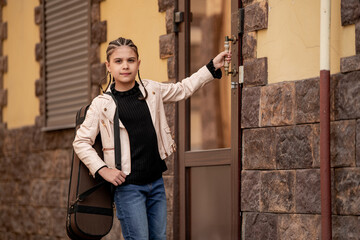 girl with a violin case reaches for a door handle she enters building
