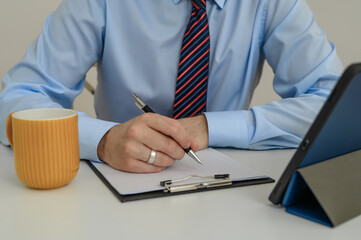 A man in an office sitting at his desk at work filling out paperwork