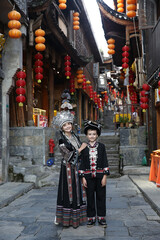 Tourist people, woman with child, kid in miao traditional national dress in Furong Ancient Town....