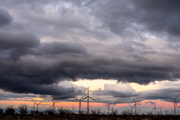 Dark clouds above wind turbines at sunset, Zaragoza, Spain, tension between natural elements and green technology for energy future