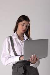 Young professional woman working on a laptop in a minimalistic studio setting during the day