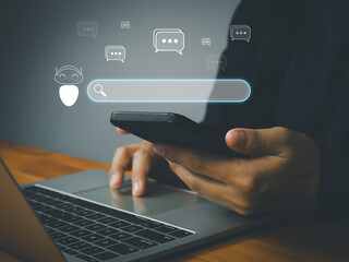 A person using smartphone and laptop with chatbot and search bar icons, symbolizing digital communication and ai assistance in modern workspace