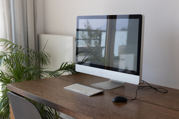 home office, modern workplace interior with computer on wooden table, computer with empty screen, keyboard with mouse and green plant, no people