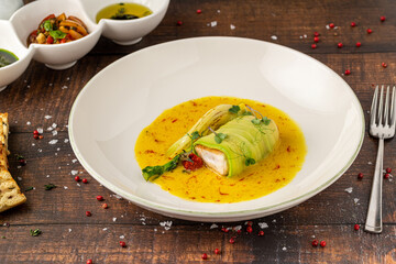 Zucchini-wrapped fish fillet in saffron-infused yellow sauce