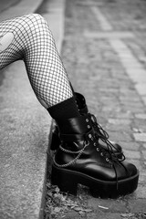 Closeup of legs of gothic girl wearing sexy stockings and black boots standing in the street