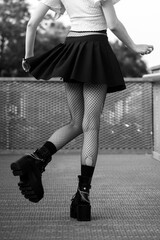 Closeup of legs of gothic girl wearing sexy stockings and black boots standing in the street