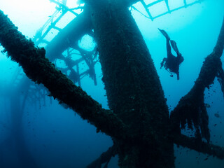 diver diving through the structure of a sunken wreck in the sea, concept of scuba diving and underwater adventure