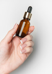 Woman hand holding cosmetic dropper bottle on white background