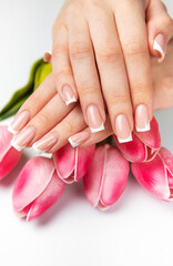 Woman showing french manicure and pink tulips on white background