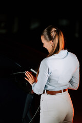 Woman charging electric vehicle in underground parking during evening hours