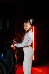 Woman charging electric vehicle in underground parking lot during evening hours