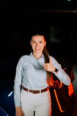 Woman happily charging electric car in underground parking lot during evening hours