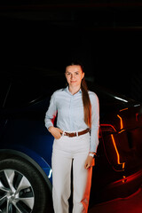 Woman charging electric car in underground parking lot during evening