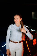 Woman charging EV in underground parking, giving a thumbs up for satisfaction