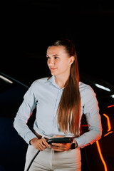 Woman charging electric car in underground parking lot at night
