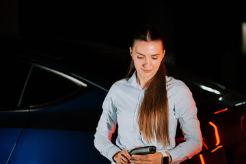 Woman charges electric car in modern underground parking lot during evening hours