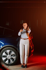 Woman charges electric car in underground parking garage while smiling confidently