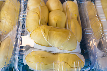 Close-up of durian fruit neatly packed in a clear plastic container, showcasing bright yellow flesh and white edible seeds