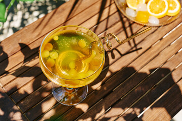 Summer refreshing orange soda drink on the table in the garden. Iced lemonade with orange slices.