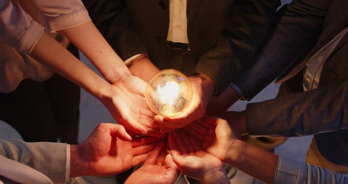 Creative team bulb holding finding problem solution as successful brainstorm, common achievement brainstorming at desk, successful business group, bright light bulb lamps, inspiration, creativity