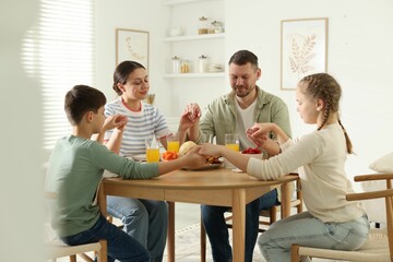 Family praying together before dinner at table indoors