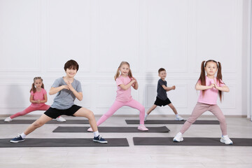 Naklejka premium Group of children practicing yoga on mats in class