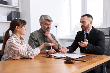 Couple having meeting with professional lawyer at wooden desk indoors