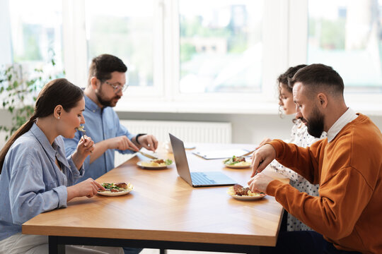 Colleagues eating and chatting during lunch break in office