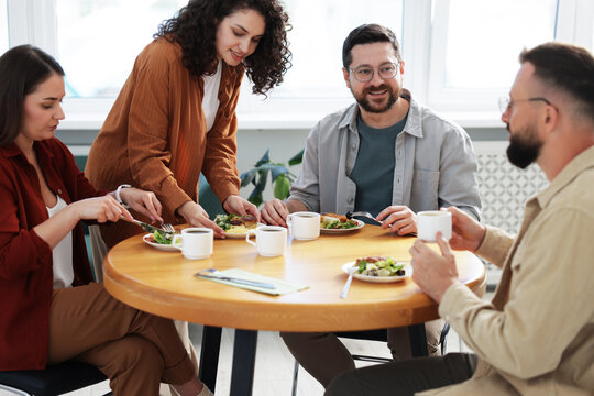 Colleagues chatting during lunch break in office - Powered by Adobe