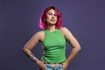 Beautiful woman with pink dyed hair on violet background