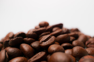 Roasted coffee beans forming a small mountain on a white background
