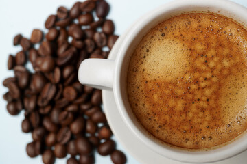 Freshly brewed coffee with crema in a white cup, accompanied by roasted coffee beans, creating a cozy and inviting scene