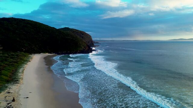 Drone aerial landscape of waves crashing onto sandy shoreline at Elizabeth Beach with headland coastline bushland trees at Booti Booti National Park in Pacific Palms Australia travel hiking tourism