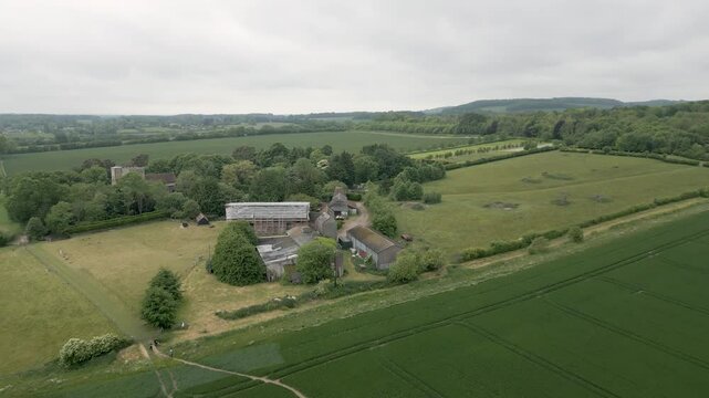 Aerial view of Kent countryside moving over a dilapidated farm and church, with walkers below