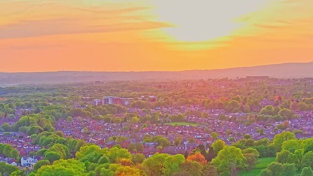 Aerial: fire sky sunset over Heaton Park with residential area in Prestwich, Manchester, England, crane down drone shot