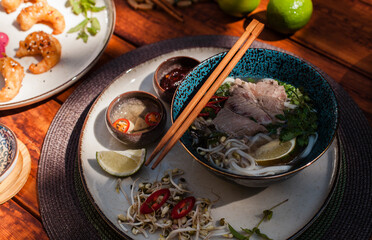 Traditional Vietnamese pho bo soup with rice noodles, beef, broth, and fresh herbs. Styled top-down shots in bowls with chopsticks and condiments