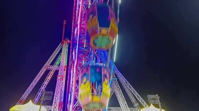 An epic cinematic view of a large luminous giant wheel or Ferris wheel rotating against the dark sky