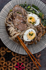 Japanese ramen soup with rice noodles, mushrooms, hard-boiled egg, and fresh toppings. Styled flat lay and close-up food photography with chopsticks