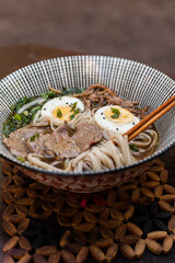 Japanese ramen soup with rice noodles, mushrooms, hard-boiled egg, and fresh toppings. Styled flat lay and close-up food photography with chopsticks