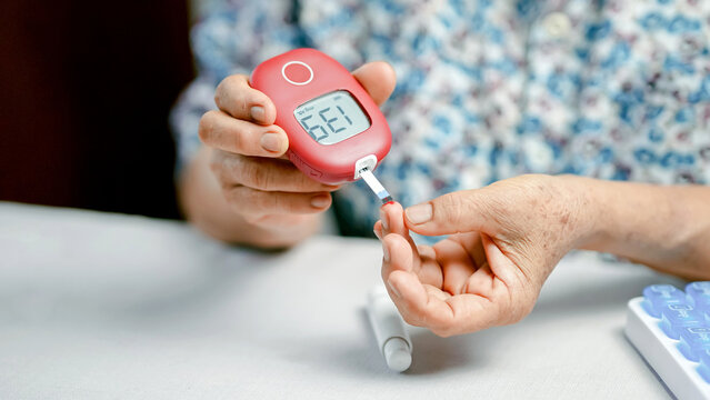 Blood glucose meter diabetes hand elderly test strip monitoring health finger close up medical device person measurement home self care healthcare senior lifestyle chronic disease prevention.
