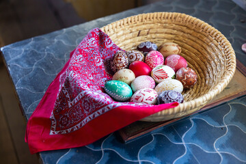 Colorful easter eggs resting in wicker basket with red bandana in Kourim, Czechia