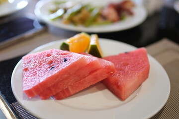 watermelon pieces on a white plate with other sweets in a buffet