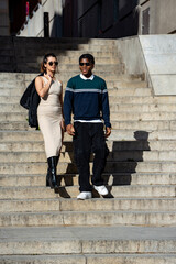 Stylish businesswoman and creative man walking down stairs in a modern city, showcasing contemporary fashion and urban lifestyle