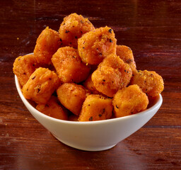 Haehnchen Wuerfel in weisser Porzellanschale auf rustikaler Holzplatte, frittiert, Geflügel, Party