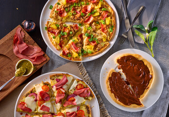Zwei herzhafte Pizzen und eine Schokoladencreme Pizza auf gedecktem Tisch mit Tischsets Topshot