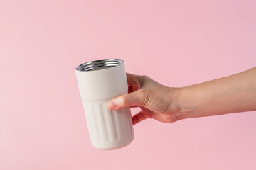 Hand holding white cup cold storage. Tumbler glass cold store. on pink background.