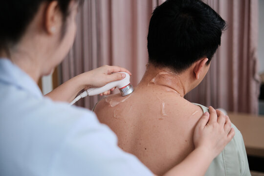 Male Asian patient is treated for healthy recovery, gel ultrasound for shoulder pain relief by female physical muscle doctor, passive medical therapy at spa clinic, and wellness messaging healthcare.