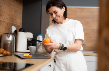 Happy Girl Cutting A Fresh Orange For Breakfast In The Kitchen