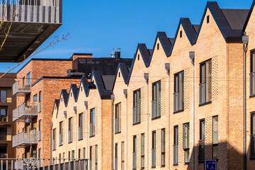 Contemporary brick housing in Ørestad, Copenhagen with geometric roofline and shadow play, architectural design and real estate concept for business visuals
